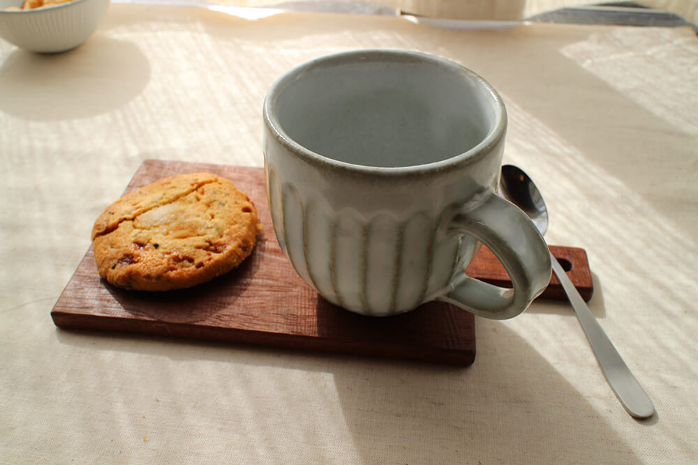 コースターの上にマグカップとクッキーをのせた画像